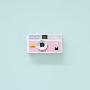 Kodak i60 35mm Film Camera Pink with flash down on teal background
