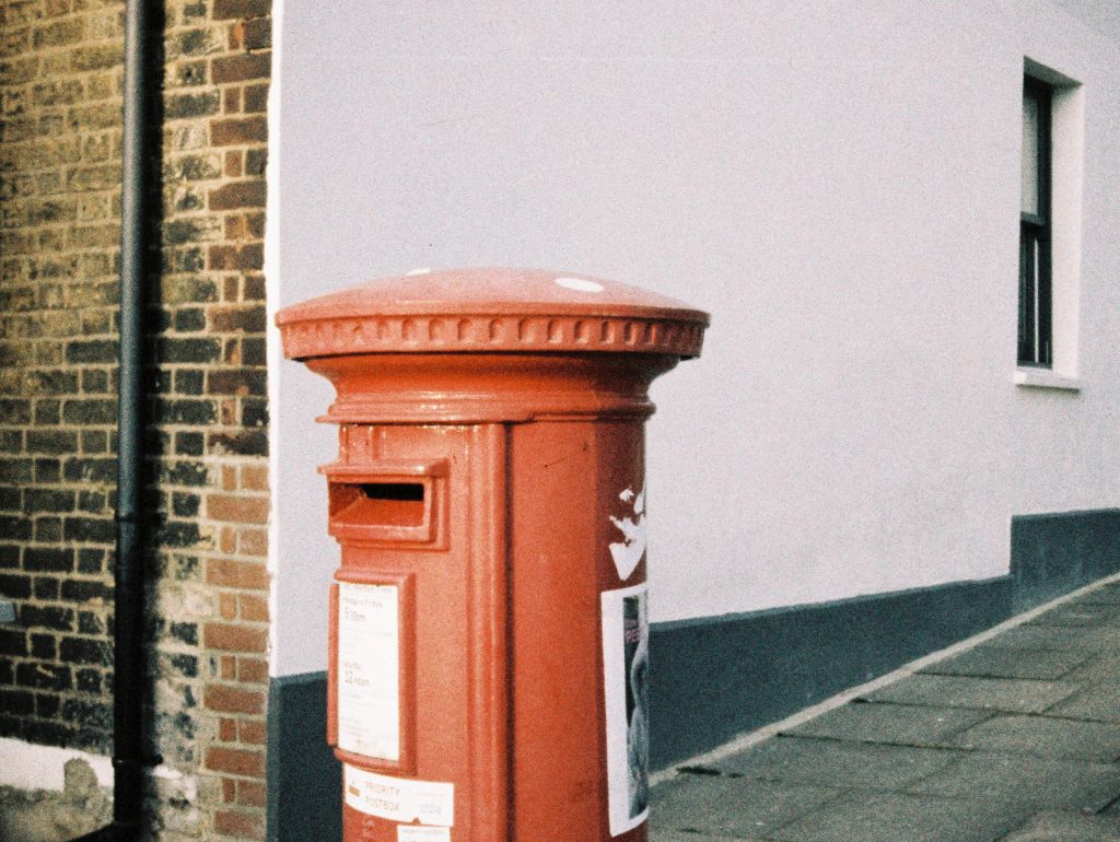Red post box on a street corner. Grainy film look. Lomo