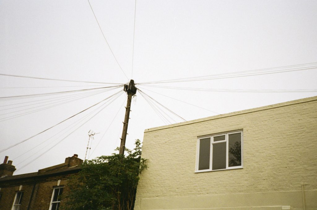 Telephone wires above a yellow building on Kodak Colorplus 35mm Film