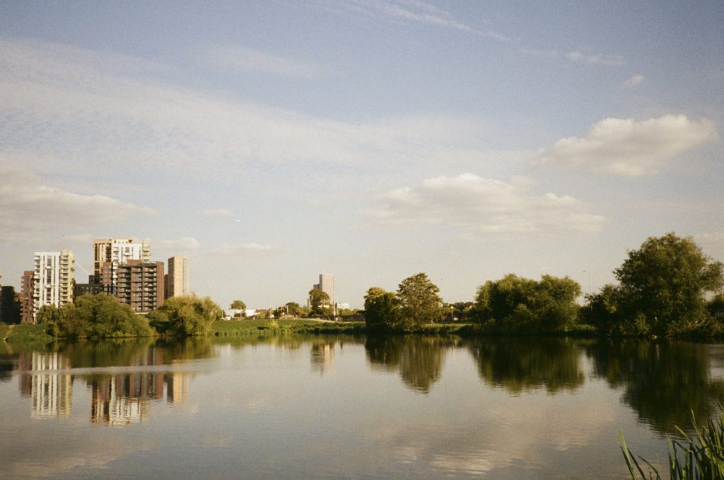 Modern tower blocks reflected in water at Walthamstow Wetlands resevoir.