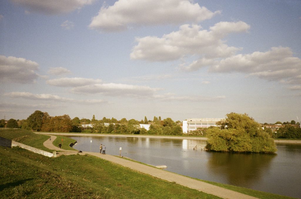 Reservoir and trees taken from a hill with people walking along the path.
